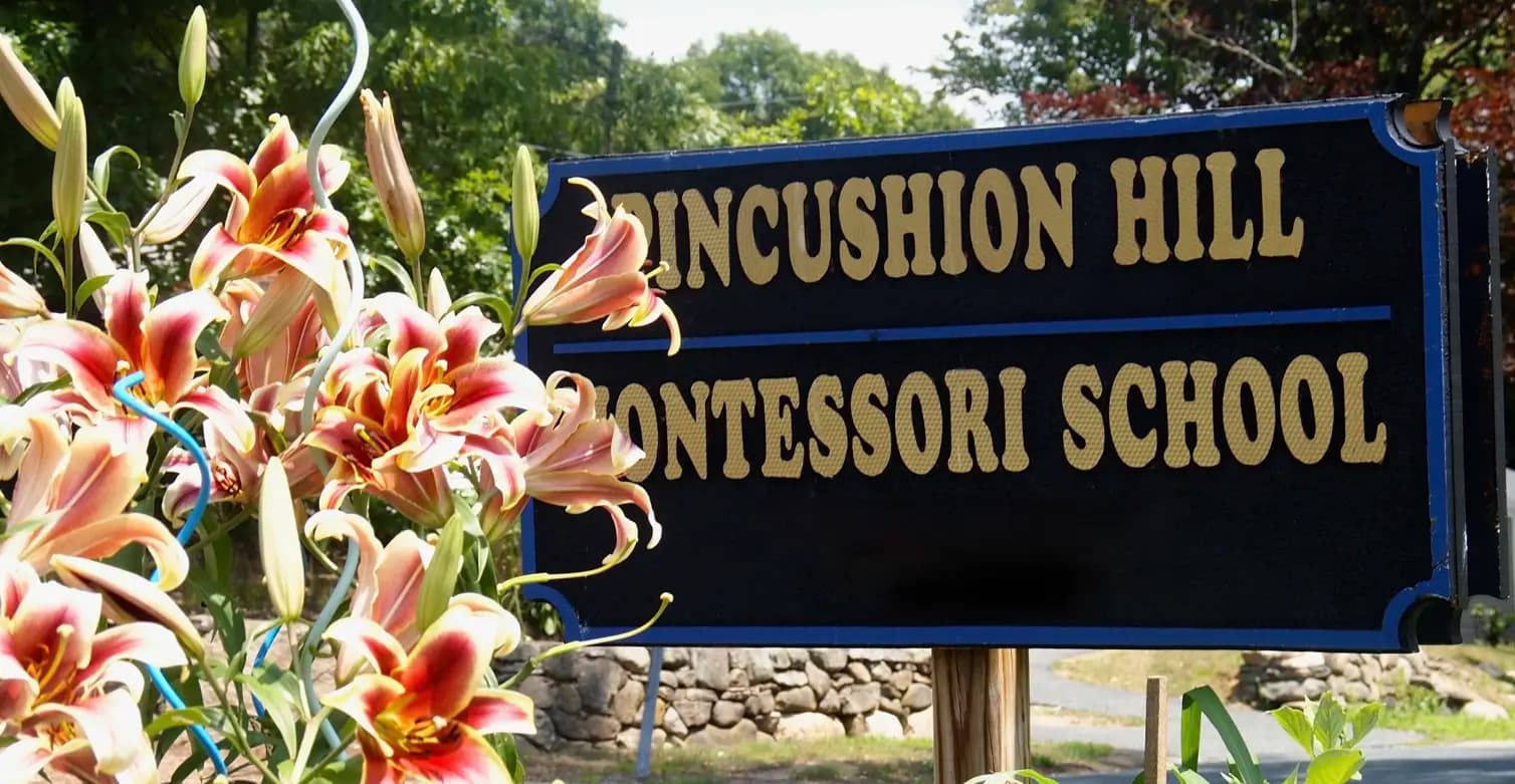The Pincushion Hill Montessori School sign, framed by lilies at the entrance.